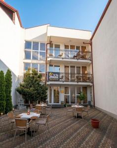 a patio with tables and chairs in front of a building at In The House Hostel in Prishtinë