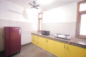 a kitchen with yellow cabinets and a red refrigerator at Hotel AR Residency in New Delhi