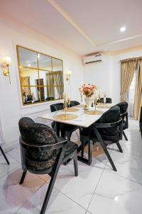 a dining room with a table and chairs and a mirror at Clarence House in Ikeja