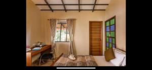 a bedroom with a desk and a bed and a window at Airyaman Hollistic Hive in Narasimharaja Puram