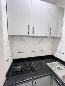 a stove top in a kitchen with white cabinets at Studio apartment in Surulere in Lagos
