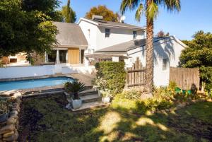 a house with a swimming pool and a palm tree at Charming B&B in Somerset West