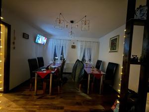 a dining room with tables and chairs and a television at Vila Rhea in Caciulata