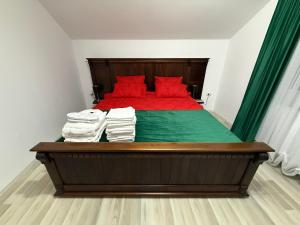 a bedroom with a bed with red pillows and green sheets at Vila Rhea in Caciulata