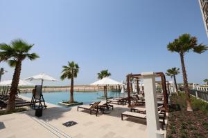 a pool with chairs and umbrellas and palm trees at Premium Studio in Yas Golf Collection in Abu Dhabi
