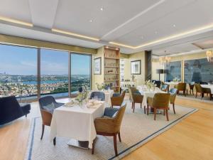 a dining room with tables and chairs and large windows at Raffles Istanbul in Istanbul