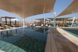 a swimming pool with chairs and umbrellas on a building at Premium Studio in Yas Golf Collection in Abu Dhabi