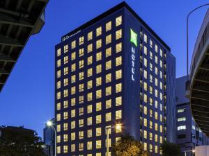 a tall black building with a green sign on it at ibis Styles Nagoya in Nagoya