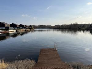 a dock in the middle of a lake with houses at Vila 512 priamo pri jazere in Šajdíkove Humence +13 photos
