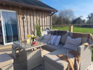 a couch and a table on a wooden deck at Waterside Cabin in Belturbet