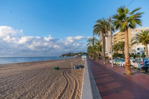 a view of a beach with palm trees and buildings at Apartamento Marina in Lloret de Mar +10 photos