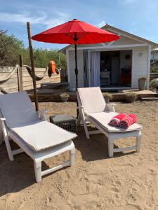 two chairs and an umbrella on a beach at Ocean Drive Deluxe Apartment with use of the Day time Beach Hut in Brean