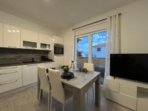 a kitchen with a table with chairs and a television at Valuna - Modern Sea View Apartment -Terrace - 4 Min to Beach - Free Parking in Jadranovo +31 photos