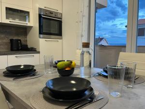 a table with black plates and bowls of fruit on it at Valuna - Modern Sea View Apartment -Terrace - 4 Min to Beach - Free Parking in Jadranovo