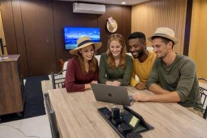 a group of people sitting around a table with a laptop at 12H Hostel in Al-ʿUla