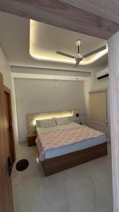 a bedroom with a bed and a ceiling fan at Mangalam Palace Vrindavan in Chhatikara