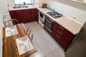 a kitchen with red cabinets and a table and a stove at Mirror Loft - Coresi District in Braşov