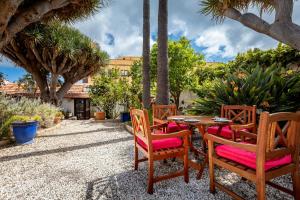 a patio with a table and chairs and palm trees at Hotel Emblemático Duque de la Torre in Arona