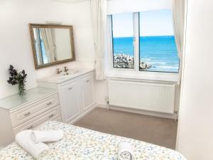 a bathroom with a bed and a sink and a window at Weymouth Bay Apartment C in Weymouth