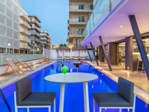 a swimming pool with a table and chairs in a building at Mercure Rhodes Alexia Hotel & Spa in Rhodes Town