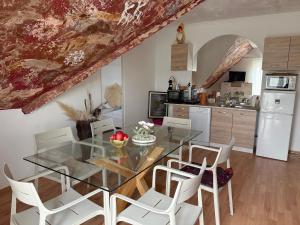 a kitchen and dining room with a glass table and white chairs at Boróka-ház Mohács in Mohács