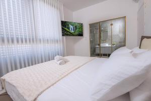 a white bedroom with a large bed and a bathroom at רויאל בוטיק טווינס 2 in Safed +15 photos