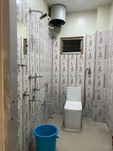 a bathroom with a toilet and a blue bucket at Veda Home's B in Agartala