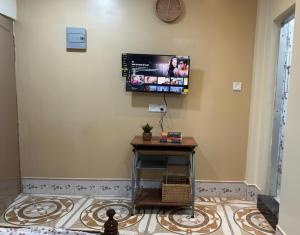 a television on a wall with a table in a room at Veda Home's B in Agartala