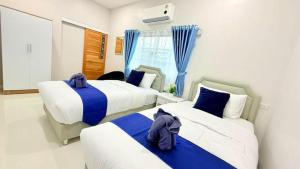 two beds in a bedroom with blue curtains at I Hug Homestay ไอฮัก ที่พักเชียงใหม่ in Ban Thap Dua