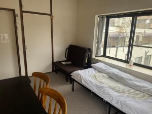 a room with a bed and a table and a window at YCS2 Guest house, good access to Shinjuku in Nishitokyo
