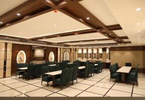 a dining room with tables and green chairs at Hotel Regalia in Bathinda