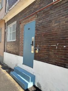 a blue door on the side of a brick building at Sinchon sweet house in Seoul