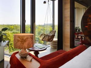 a room with a chair and a lamp and a window at 25hours Hotel Bikini Berlin in Berlin