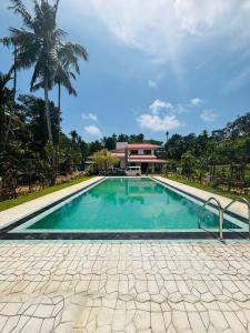 a swimming pool in front of a house with a palm tree at Villa Paddy Breeze in Galle