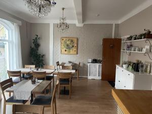 a dining room with tables and chairs and a kitchen at Kågeröds Värdshus Tre Stjärnor in Kågeröd
