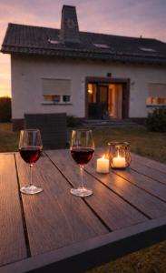 two glasses of wine on a wooden table with a candle at Ferienwohnungen Hoheeifel Nähe Nürburgring Platz für bis zu 10 Personen ,Verleih von zwei E-MTB möglich in Kelberg