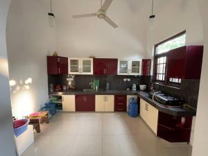 a kitchen with red cabinets and a ceiling fan at Mayon's Home in Kalutara