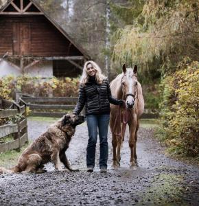 a woman walking a horse and a dog on a dirt road at Dom wakacyjny Chata Babci Wolf in Strzebowiska