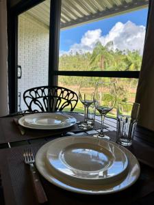 a table with two plates and wine glasses on it at Hospedagem Terras Raras Patrimônio da Penha in Divino de São Lourenço