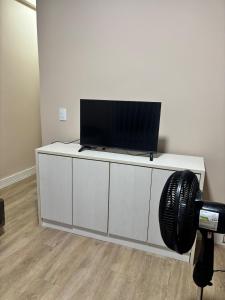 a flat screen tv sitting on a white cabinet at Kitnet bem equipada para 2 pessoas in Curitiba