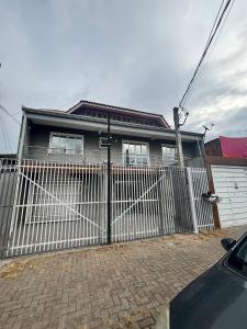 a house with a white gate and a fence at Kitnet bem equipada para 2 pessoas in Curitiba