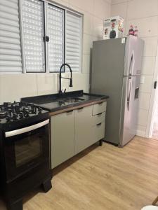 a kitchen with a stove and a refrigerator at Kitnet bem equipada para 2 pessoas in Curitiba