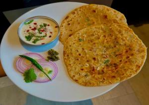 a plate with two naan bread and a bowl of soup at Hotel Brij Stone in Vrindāvan