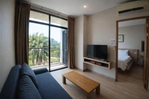 a living room with a blue couch and a large window at Sugar Palm Residence in Phuket