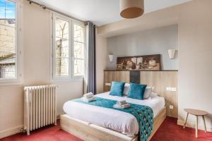 a bedroom with a large bed with blue pillows at Logis Hôtel Restaurant Cristal in Saumur
