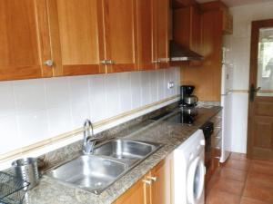 una cocina con fregadero de acero inoxidable y armarios de madera en Apartamento Martín, en Mora de Rubielos