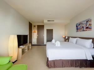 a bedroom with a large white bed and a television at Satun Le Grand - โรงแรม สตูล เลอแกรนด์ in Ban To La Nua