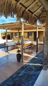 a patio with benches and a straw umbrella at Vila Lençóis Residence in Santo Amaro