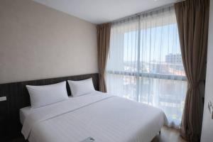 a bedroom with a white bed and a large window at Sugar Palm Residence in Phuket