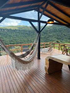 a hammock on a deck with a view of the mountains at Cabana Refúgio da Montanha in Alfredo Wagner